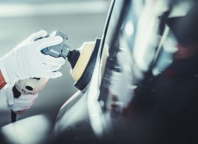 Professional Detailer Automotive Worker Polishing Vehicle Body After Waxing Close Up Photo