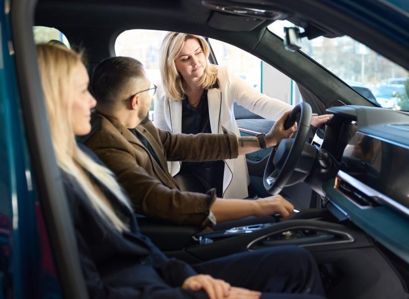 Consultant who sells cars shows the inside of the car that a young couple has chosen