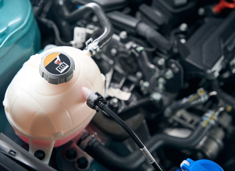 Close up photo of antifreeze tank, car with an open hood in tire shop